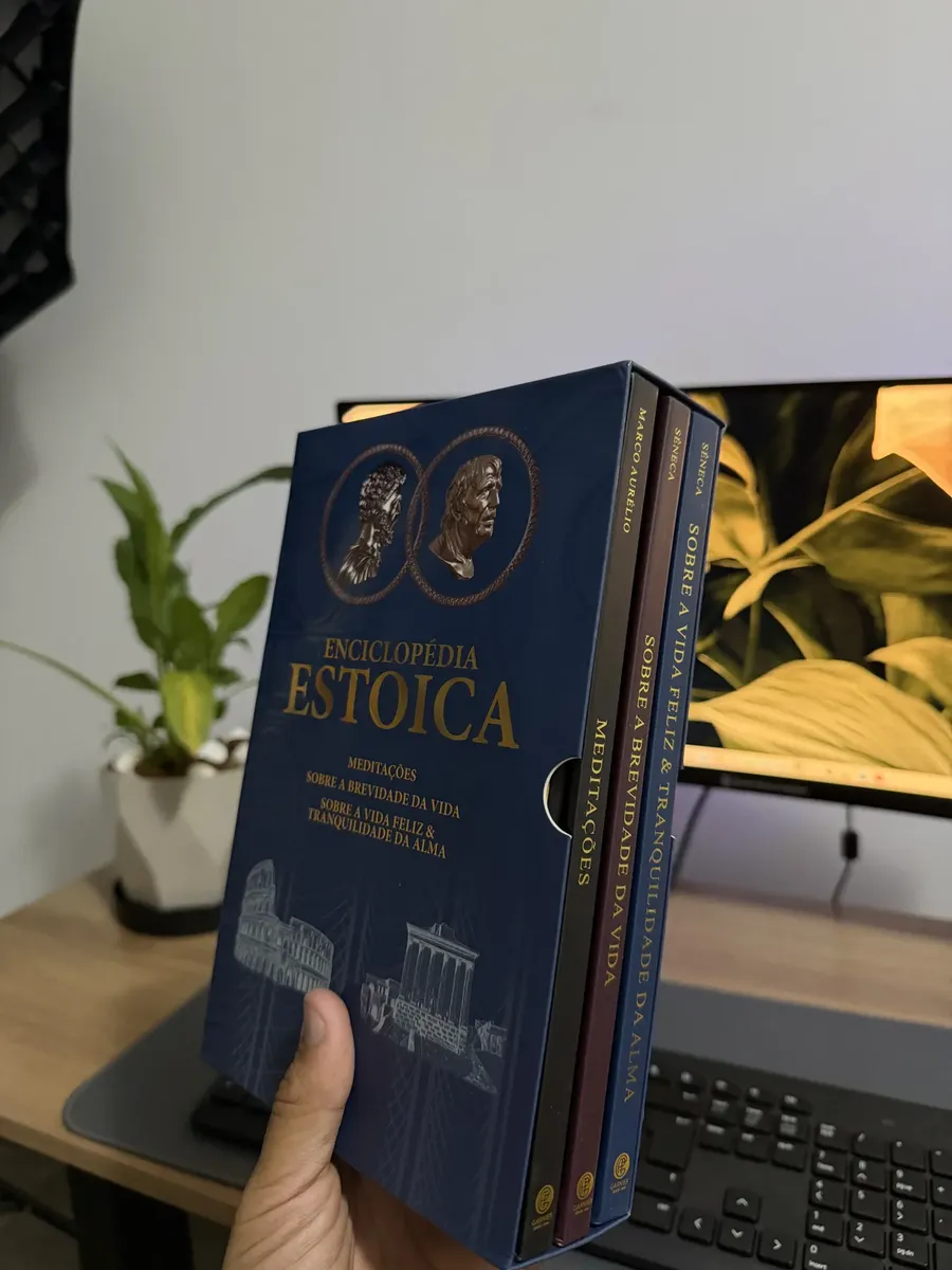 Box Biblioteca Estoica segurado na mão por cliente em ambiente de escritório