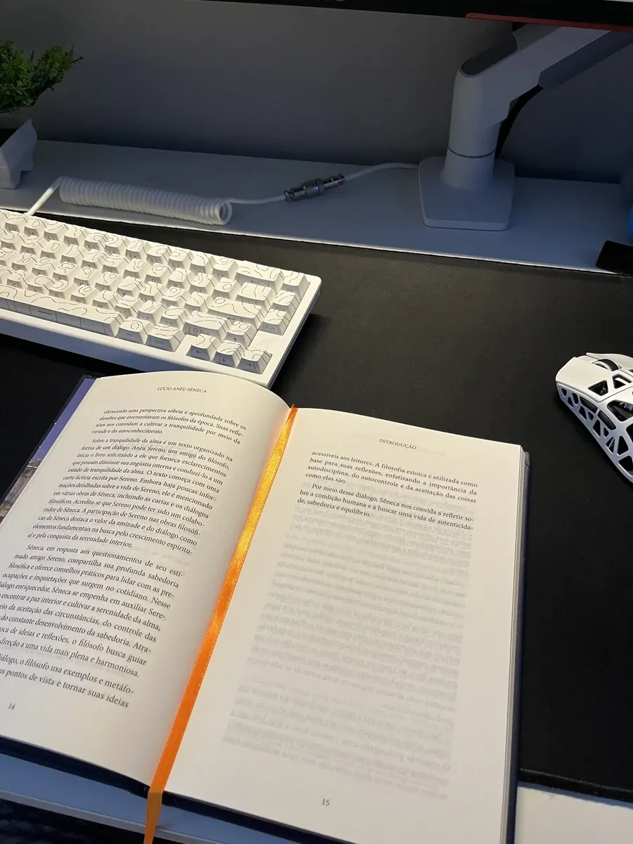 Livro aberto com marcador de fitilho laranja sobre mesa de leitura